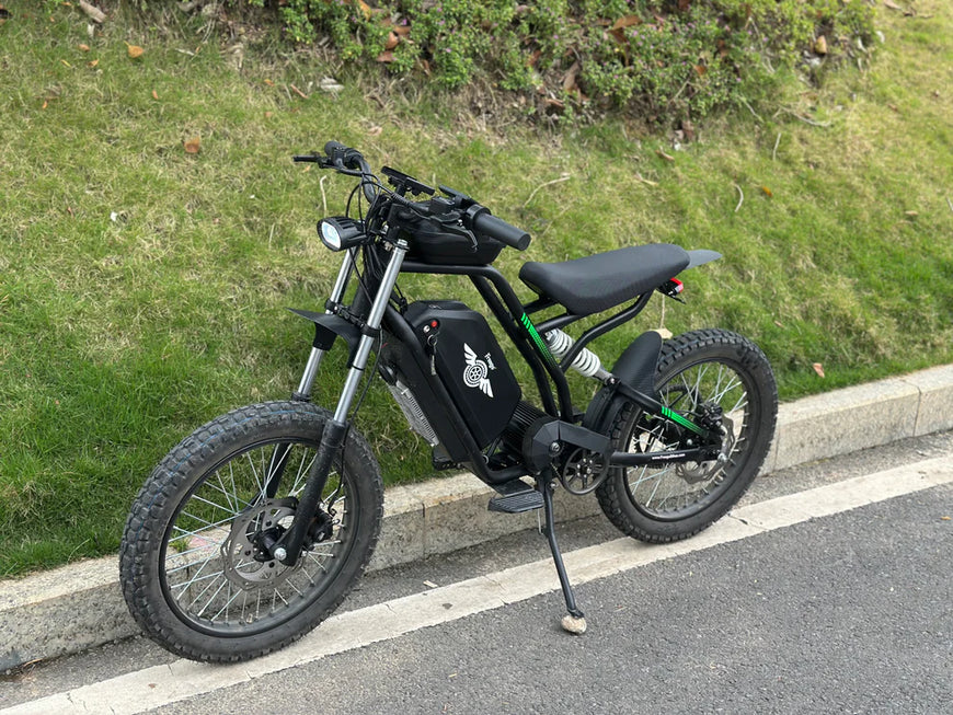Black electric bike parked on a road next to a grassy area. Freego Nova 3 Mid-Drive All-Terrain Dirt eBike