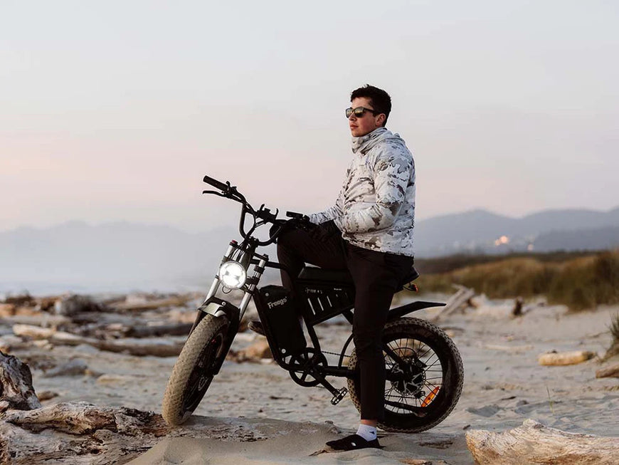 Person sitting on a motorcycle in a desert landscape with mountains in the background. Freego S1 Cafe Racer eBike