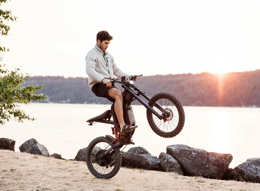 Man riding a dirt bike by a lake with a scenic background. Freego X2 Pro All-Terrain Dirt eBike