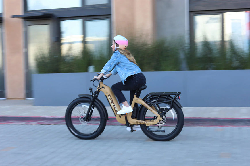 Person riding a wooden electric bike on a sidewalk with a building in the background. CYKE Lynx Commuter EBike