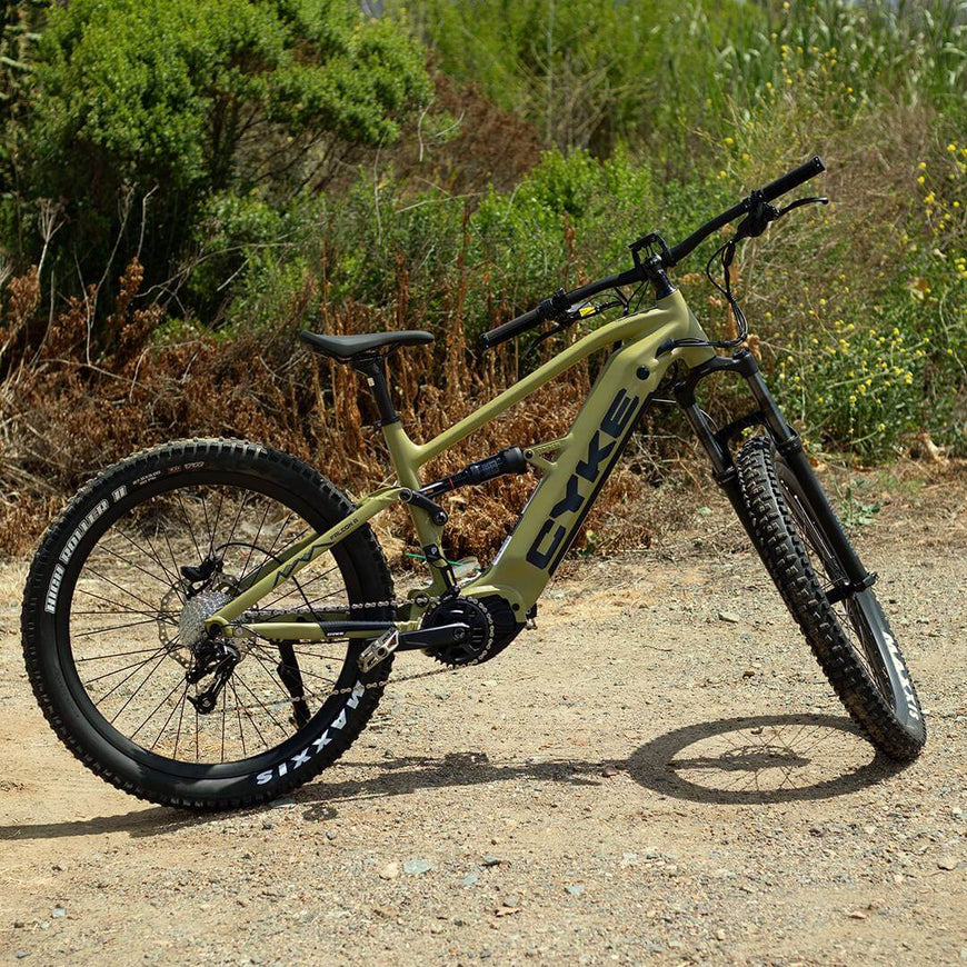 Electric bike on a dirt path with greenery in the background. CYKE Falcon A Full Suspension eBike