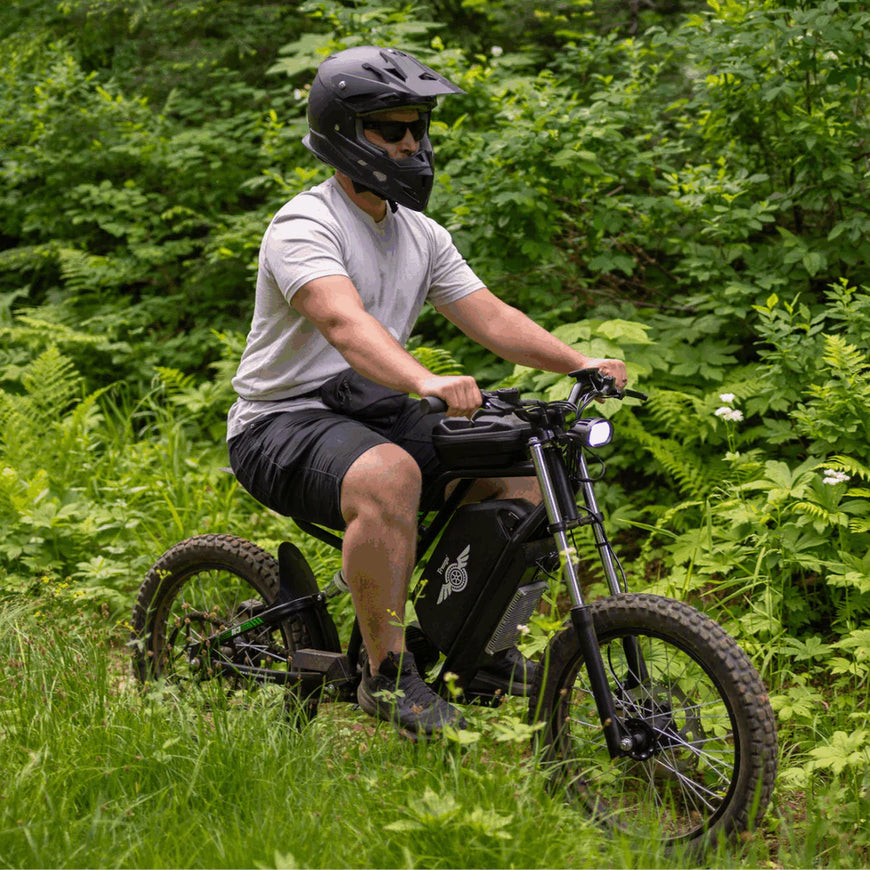 Person riding a bike in a forested area. Freego Nova 3 Mid-Drive All-Terrain Dirt eBike