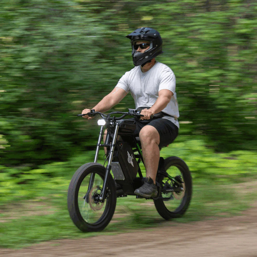 Person riding a black electric bike on a trail with greenery in the background Freego Nova 3 Mid-Drive All-Terrain Dirt eBike