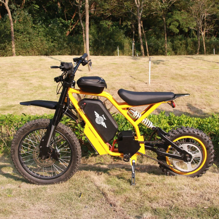 Yellow electric bike on a grassy field with trees in the background. Freego Nova 2 Mid-Drive Youth Electric Dirt Bike