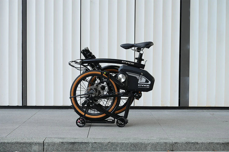 Foldable electric bike against a modern building facade. CYKE Kingfisher Mid-Drive Folding eBike