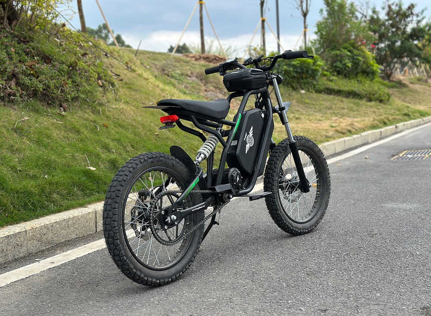 Black electric bike on a road with greenery in the background. Freego Nova 3 Mid-Drive All-Terrain Dirt eBike