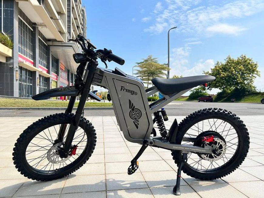 Electric bike on a sidewalk with buildings and trees in the background. Freego X2 Pro All-Terrain Dirt eBike